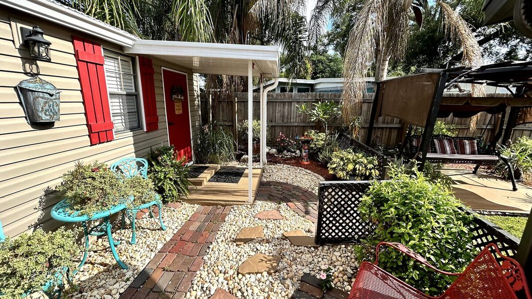 Brick walkway leading past the shed with red shutters and gardens